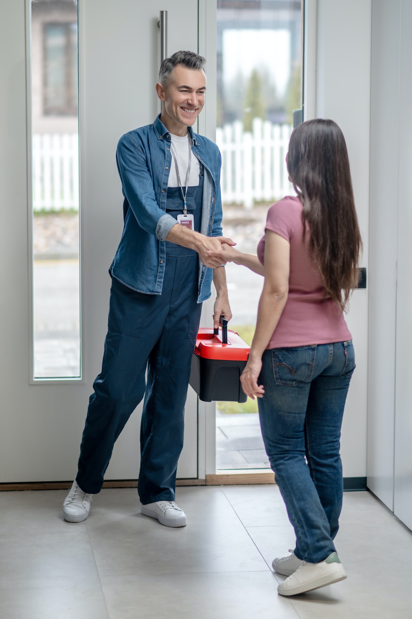 Man and woman shaking hands standing in house at door