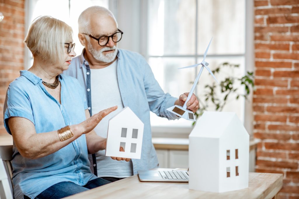 Senior couple with house models and toy wind turbine at home